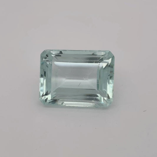 Rectangular greenish-blue gemstone on a gray background